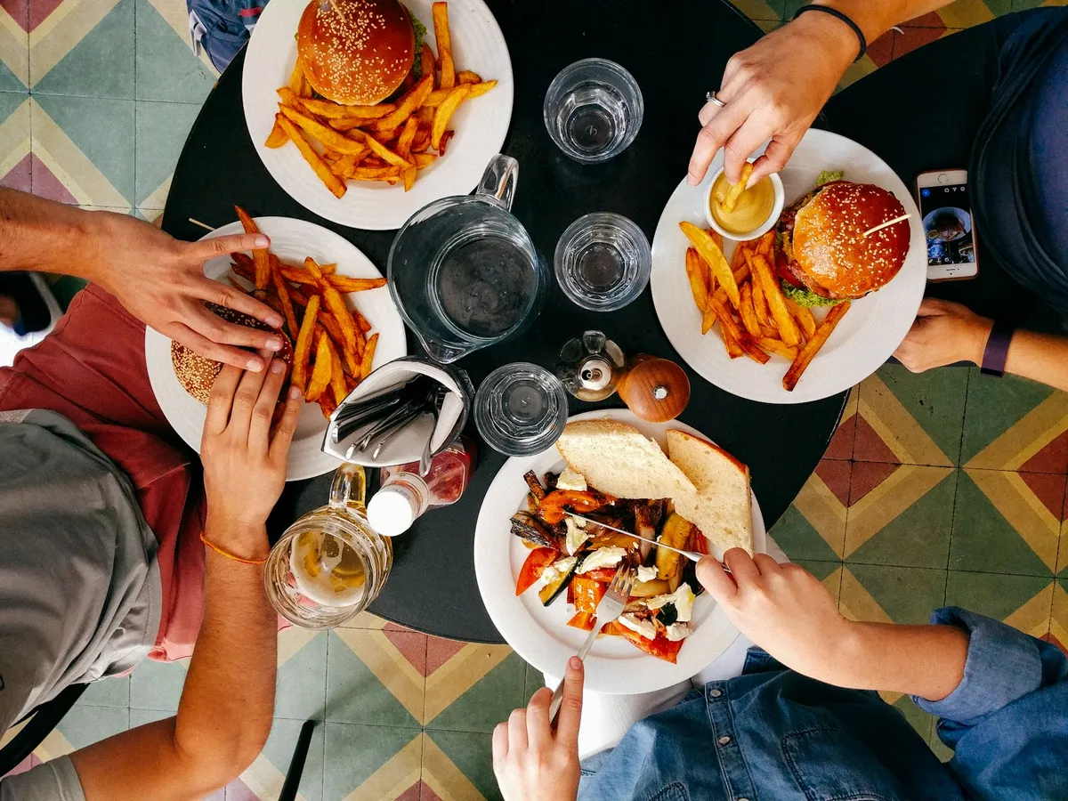 Vue de dessus d'une table de restaurant avec burgers, frites et un téléphone
